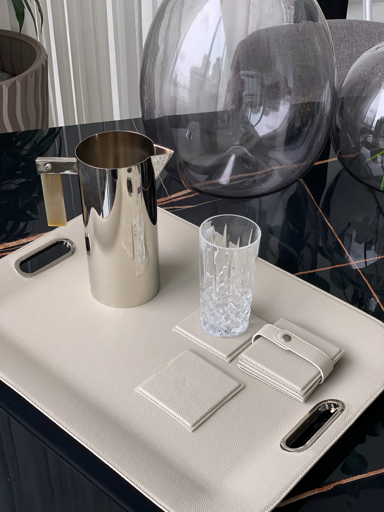 Gray large serving tray with metal handles set with glassware for entertaining