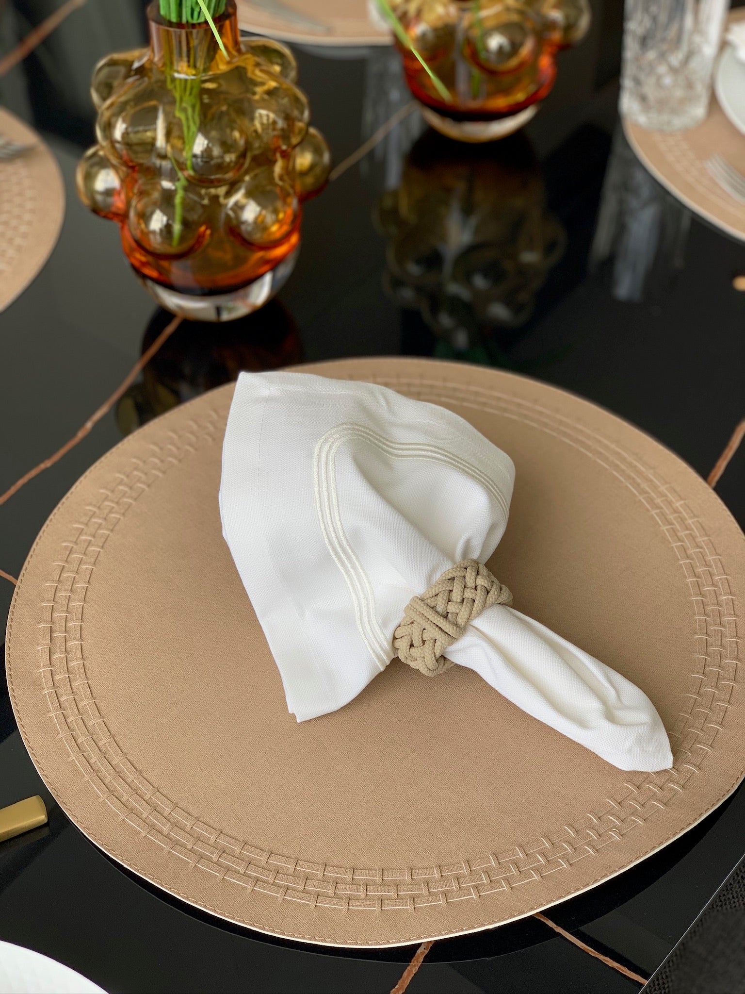 Brown Stitched leather band detail on taupe round placemat, luxury tableware, housewarming gift idea with a cloth white napkin