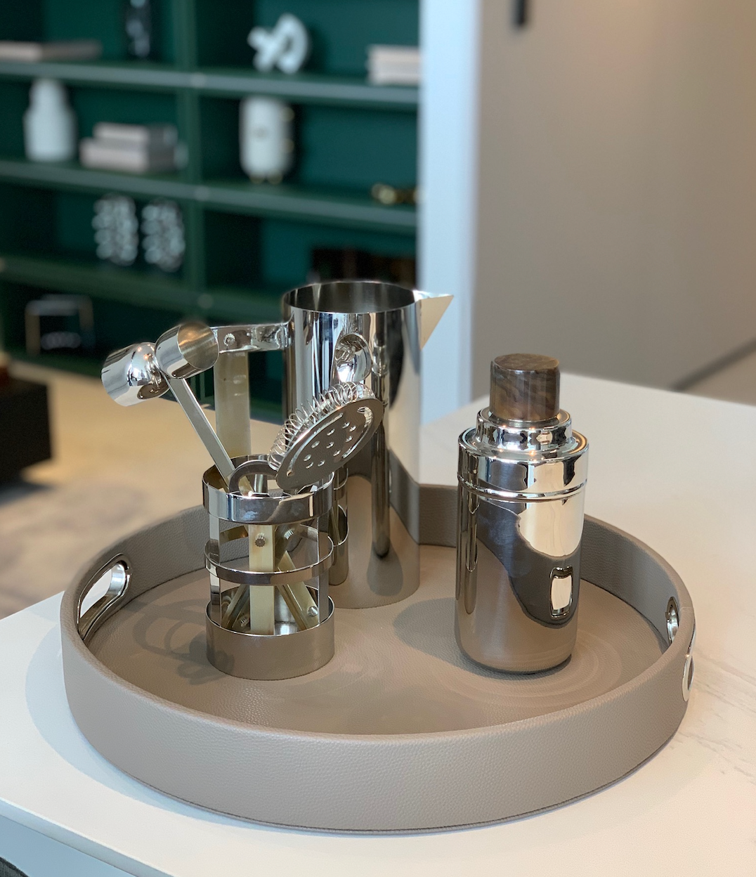 Round Design Tray with chrome handles styled with a chrome mixing pitcher, strainer, and cocktail shaker for a bar cart moment